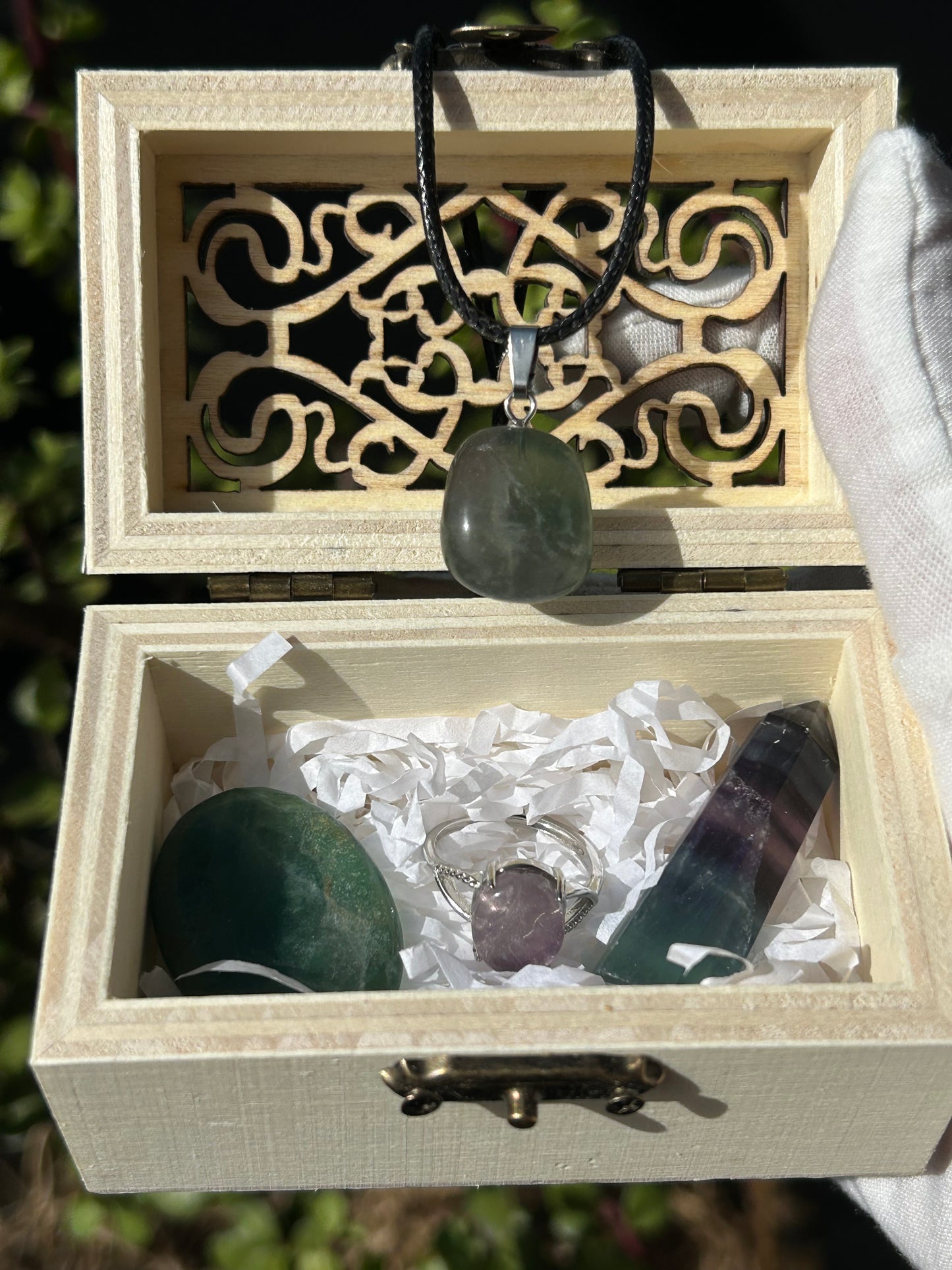 wooden box containing fluorite necklace, ring, thumbstone and crystal point