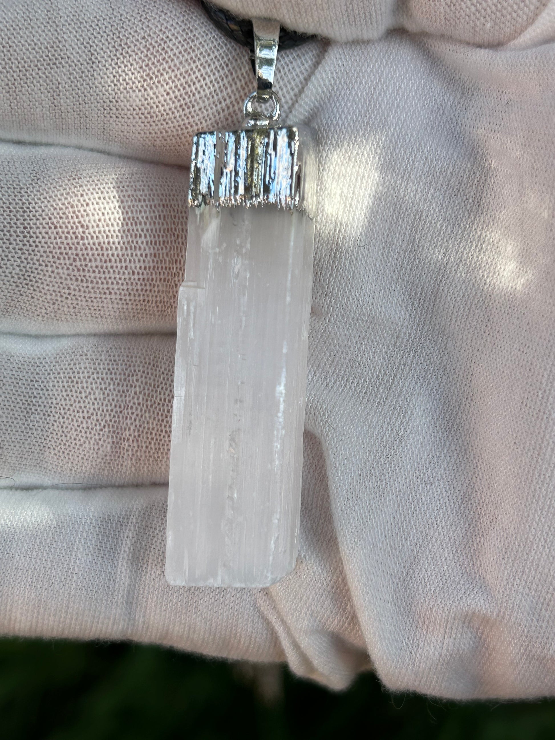 irregular selenite cuboid pendant with silver detail and black cord necklace