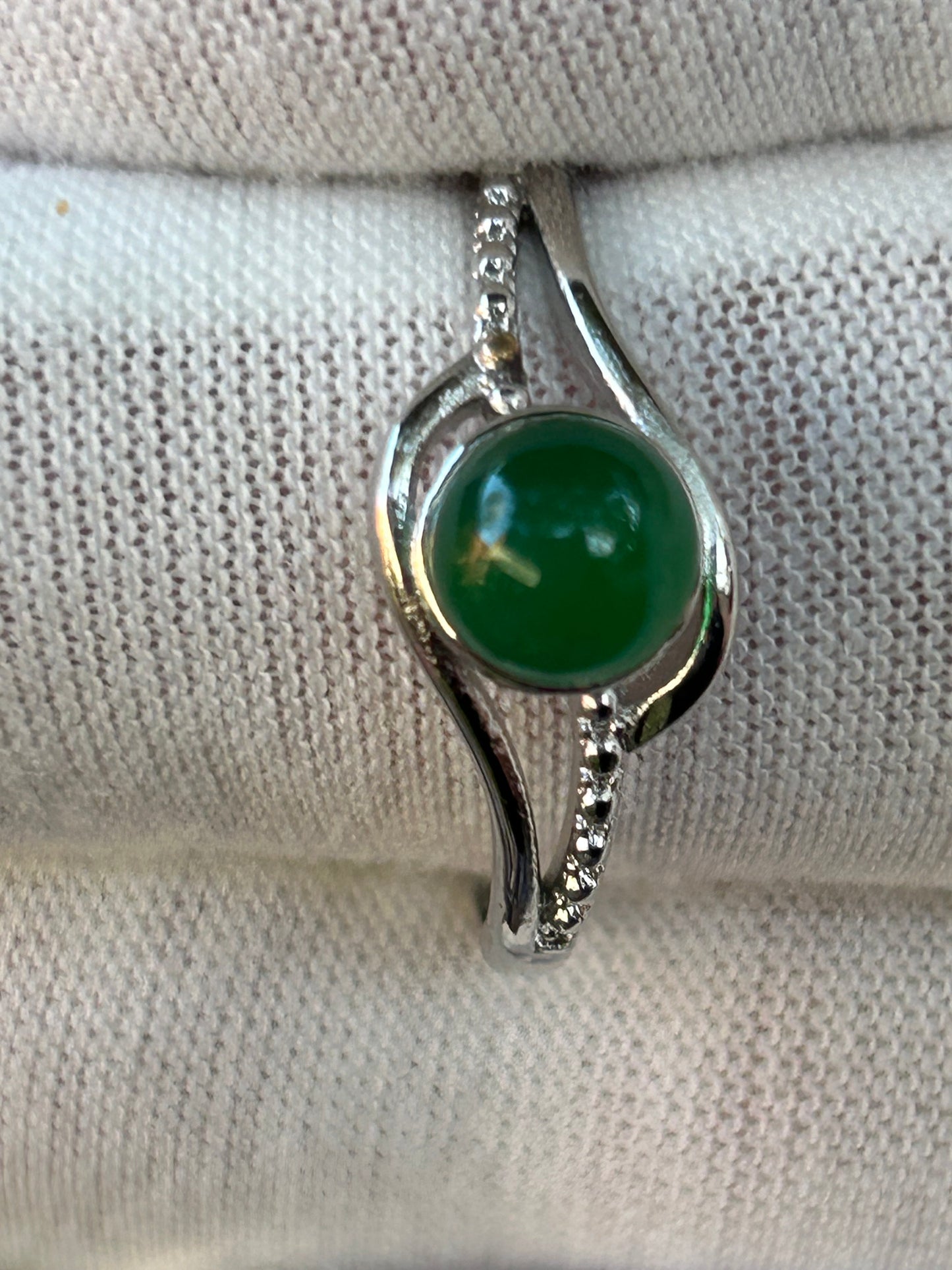 Delicate round polished green jade set in ornate adjustable silver ring