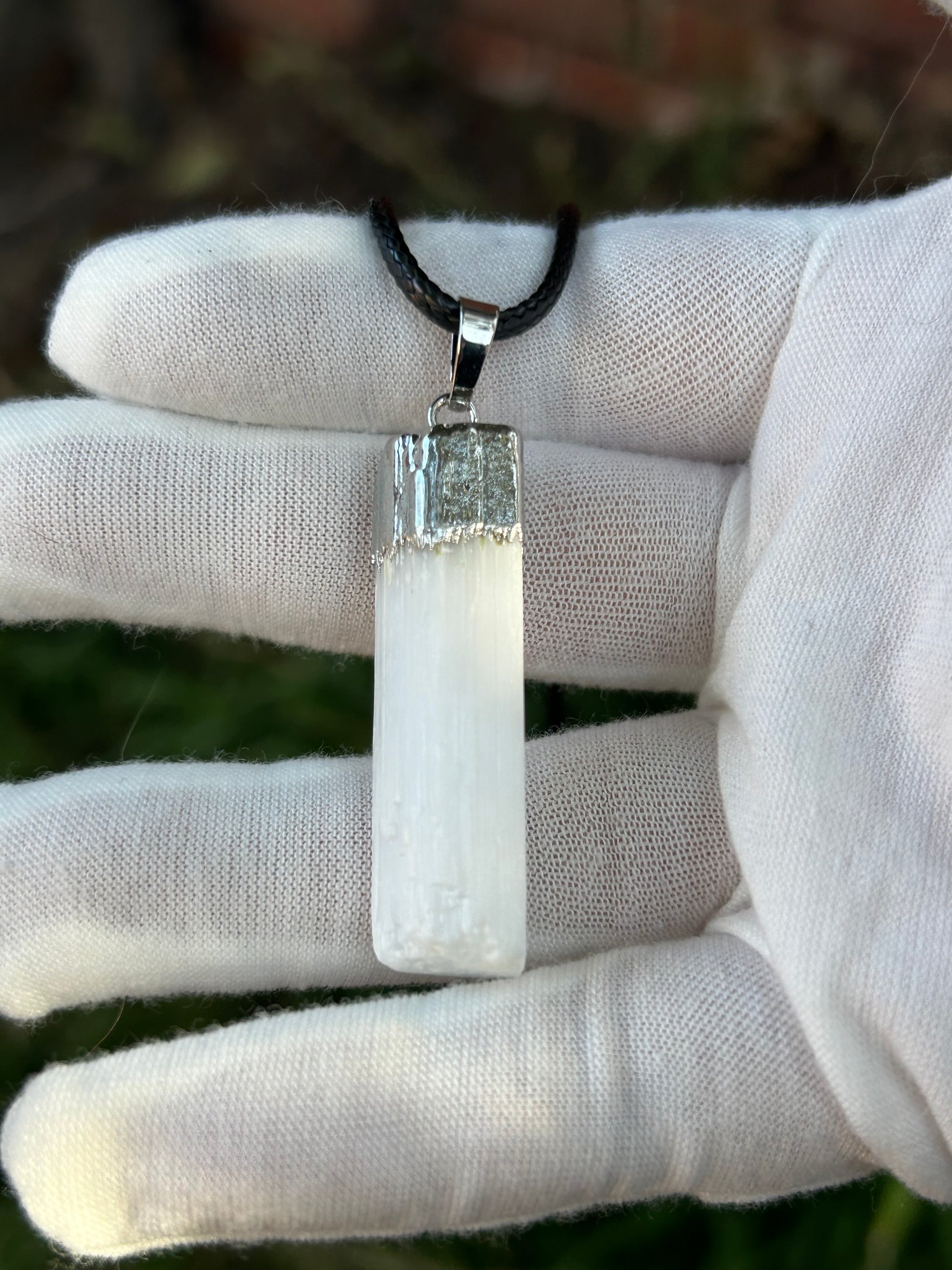 irregular selenite cuboid pendant with silver detail and black cord necklace