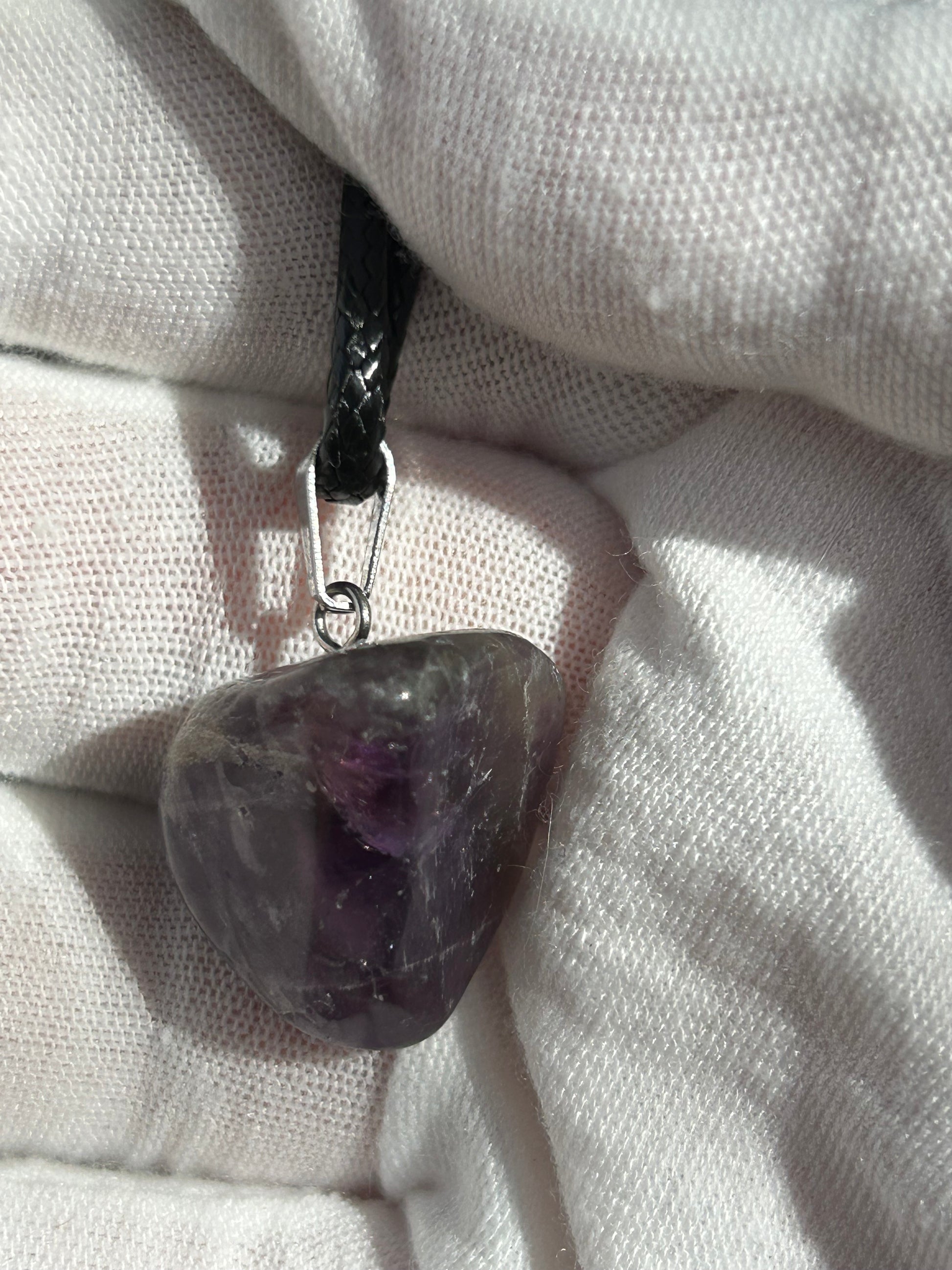 small polished dream amethyst crystal pendant with silver pendant attachment and black cord necklace