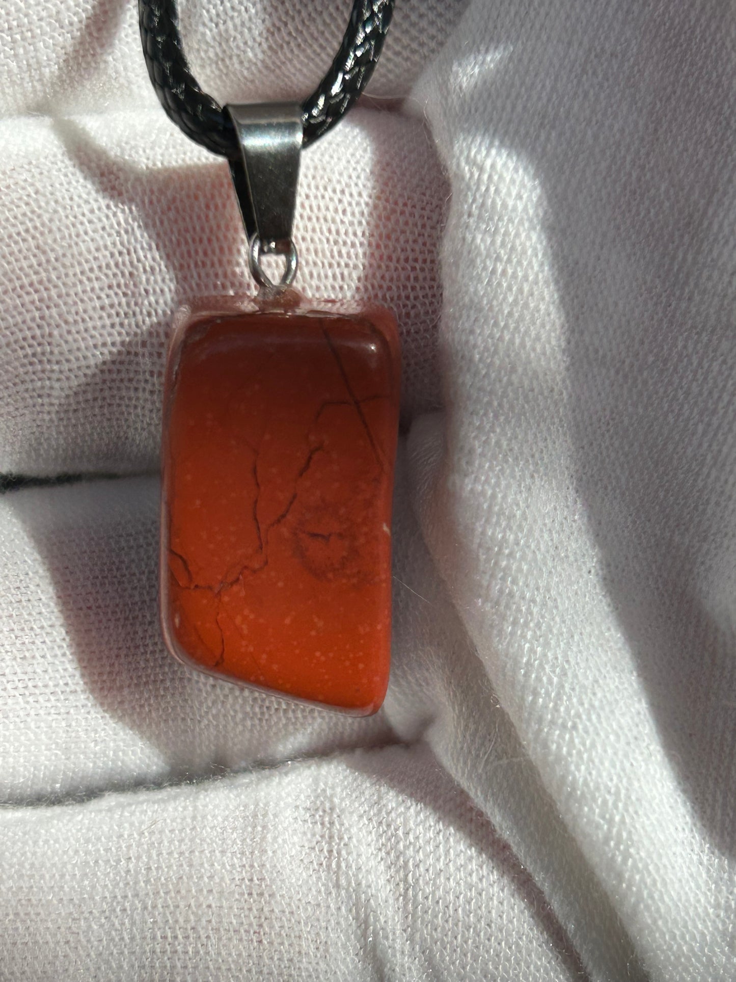 Small Red Jasper Polished Pendant with silver pendant attachment and black cord necklace