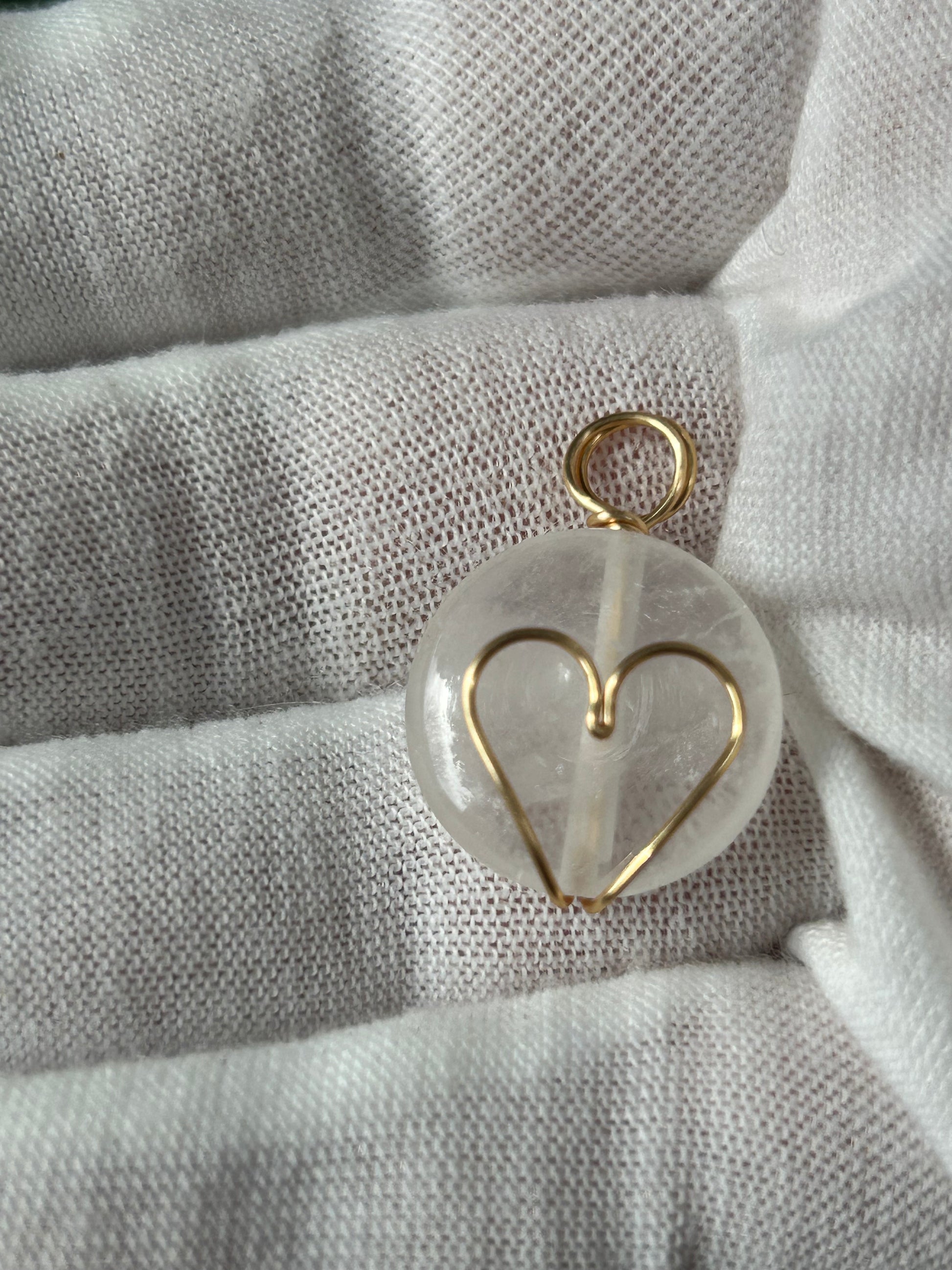 Small round polished clear quartz pedant or charm with wrapped gold heart