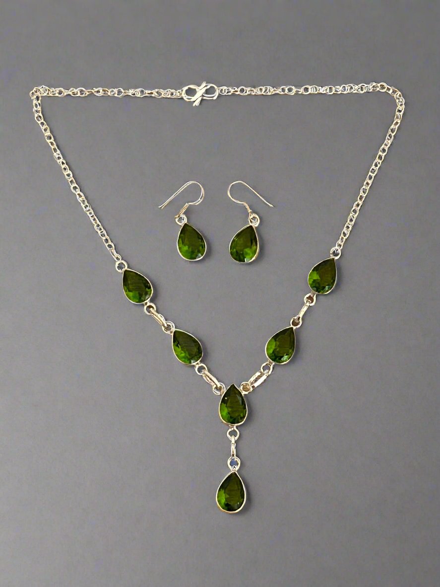 Green Peridot and 925 Sterling Earrings and and Necklace Set. The necklace has 6 faceted peridot gems  cut in a water drop shape and the earrings each have one gem