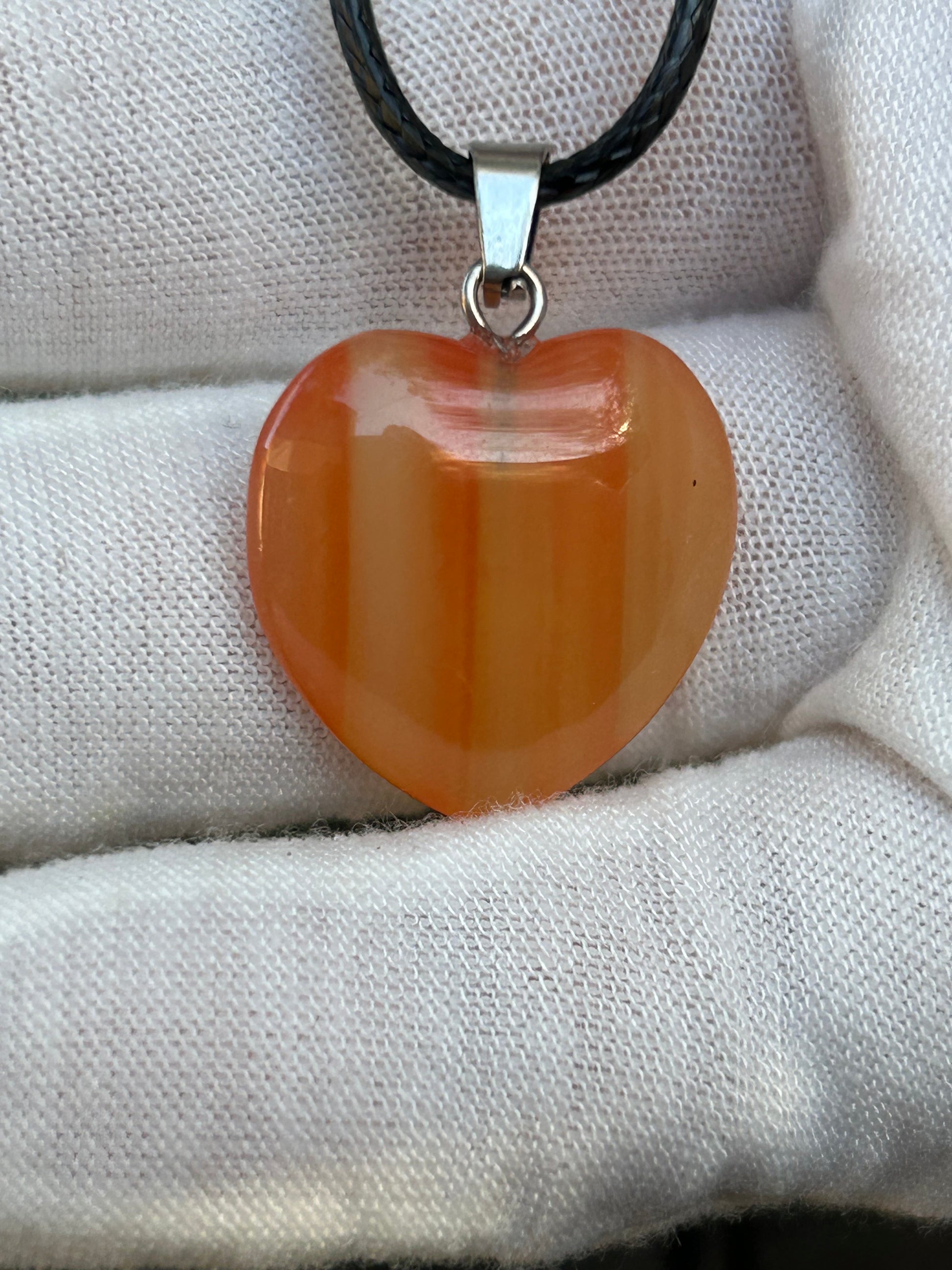 orange agate polished heart pendant with silver pendant attachment and black cord necklace