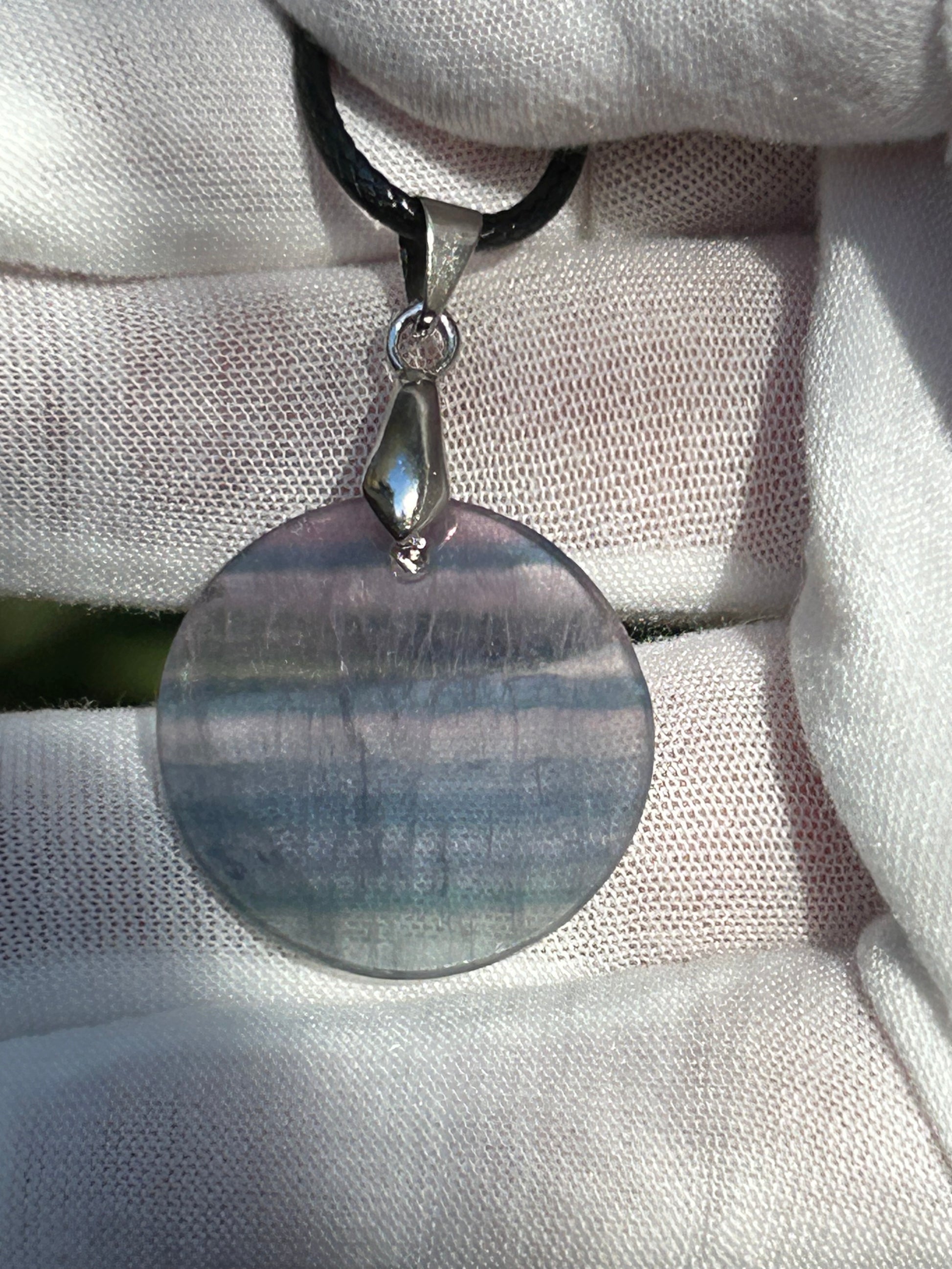 Rainbow Fluorite Circular Pendant with silver pendant attachment and black cord necklace