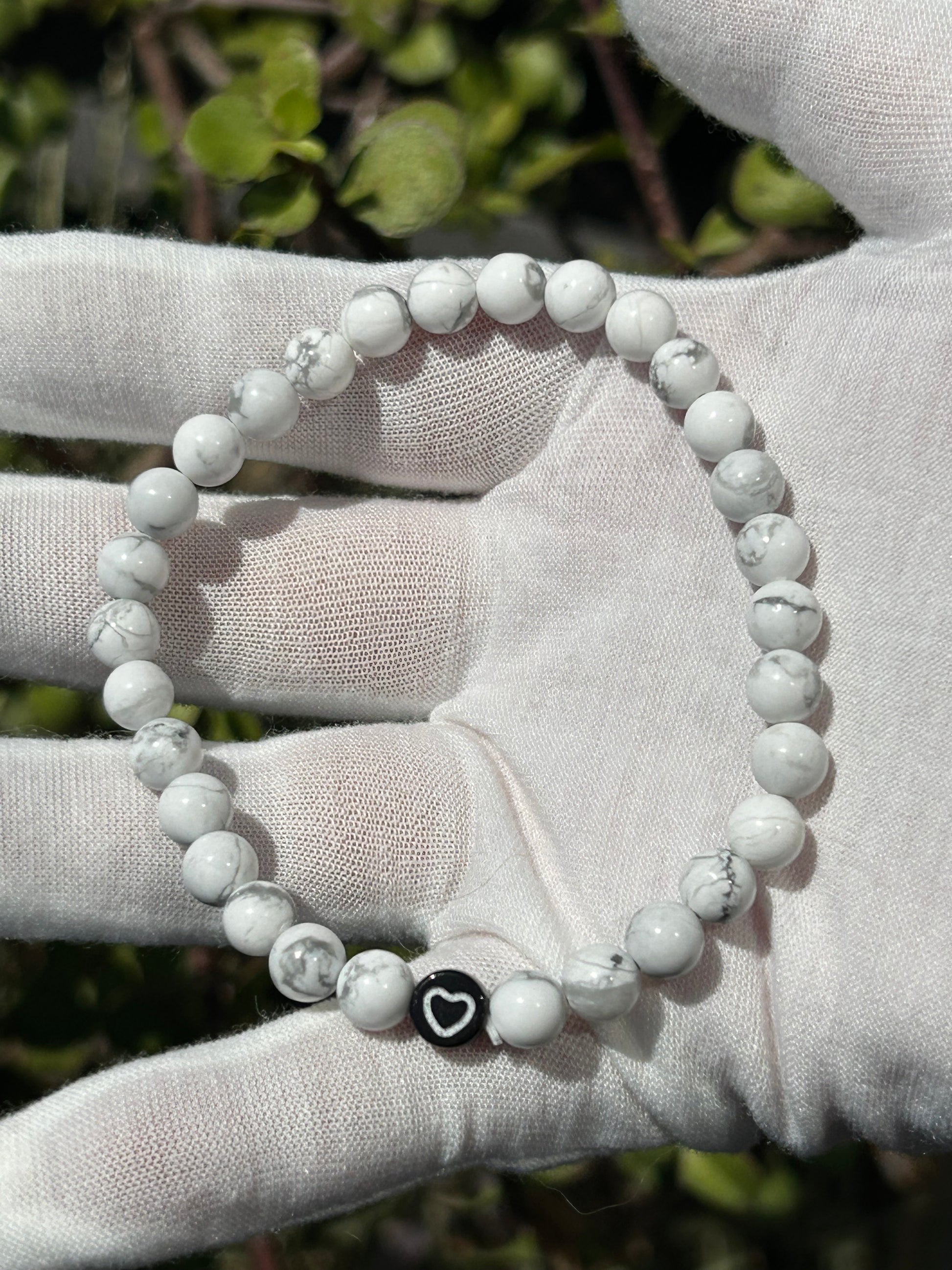 Howlite bead bracelet with small black bead with white heart on it.